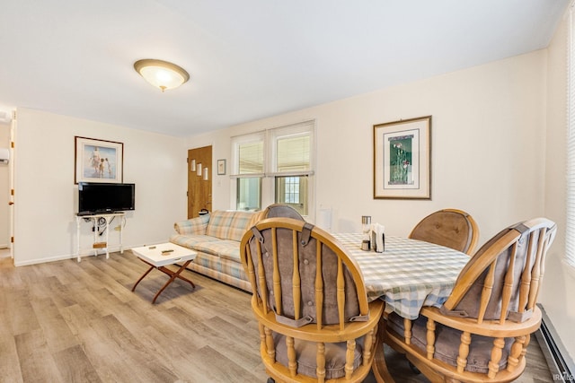 dining area with a baseboard heating unit and light hardwood / wood-style flooring