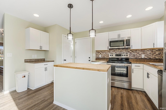 kitchen with a kitchen island, appliances with stainless steel finishes, decorative light fixtures, white cabinetry, and wooden counters