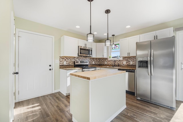 kitchen with stainless steel appliances, decorative light fixtures, a kitchen island, and white cabinets