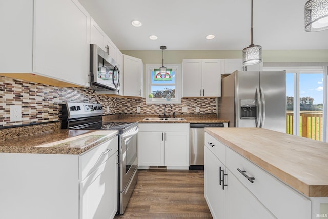 kitchen featuring sink, wooden counters, hanging light fixtures, appliances with stainless steel finishes, and white cabinets