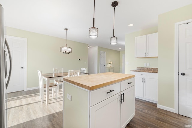 kitchen with white cabinetry, a center island, pendant lighting, and butcher block countertops