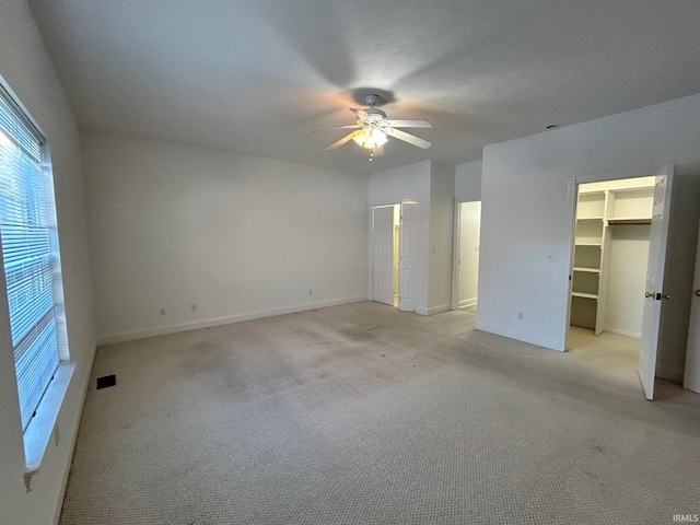 interior space featuring a spacious closet, light carpet, and ceiling fan