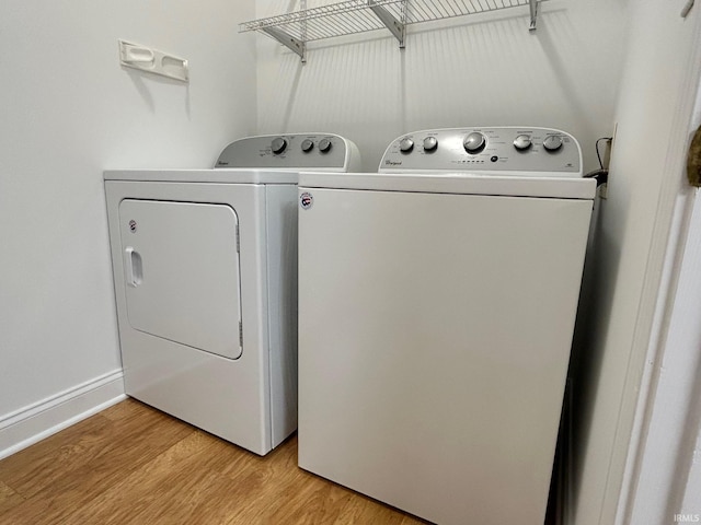 clothes washing area featuring separate washer and dryer and light hardwood / wood-style flooring