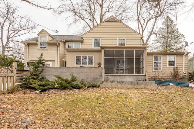 back of property with a yard and a sunroom