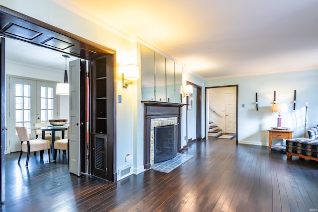 living room with crown molding, dark wood-type flooring, a fireplace, and french doors