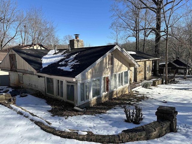 view of snowy exterior with a sunroom