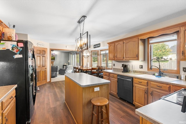 kitchen featuring dark wood-type flooring, sink, black fridge, dishwasher, and a kitchen island