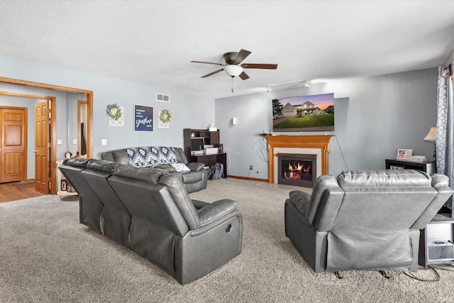 carpeted living room featuring ceiling fan, track lighting, and a textured ceiling