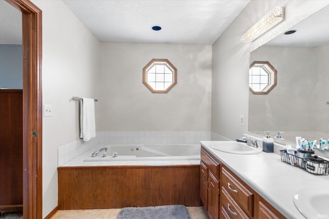 bathroom with vanity, a textured ceiling, and a tub to relax in