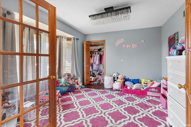 bedroom with a closet, a textured ceiling, and french doors