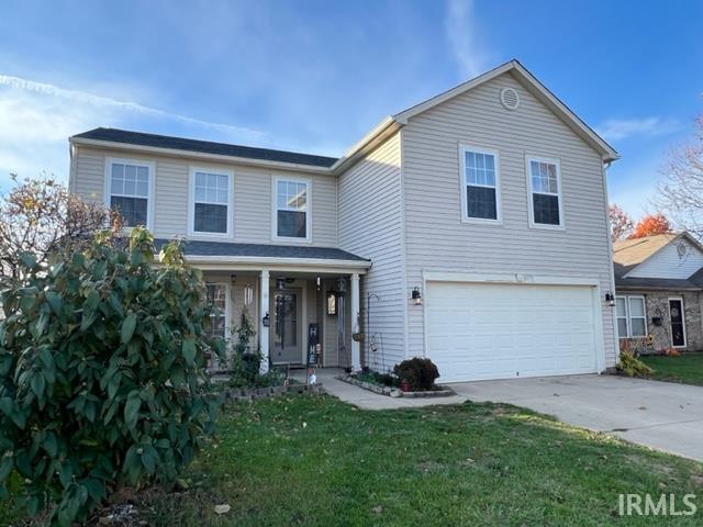 view of front property featuring a garage, covered porch, and a front lawn