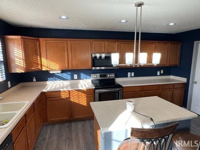 kitchen with sink, hanging light fixtures, a textured ceiling, appliances with stainless steel finishes, and dark hardwood / wood-style floors