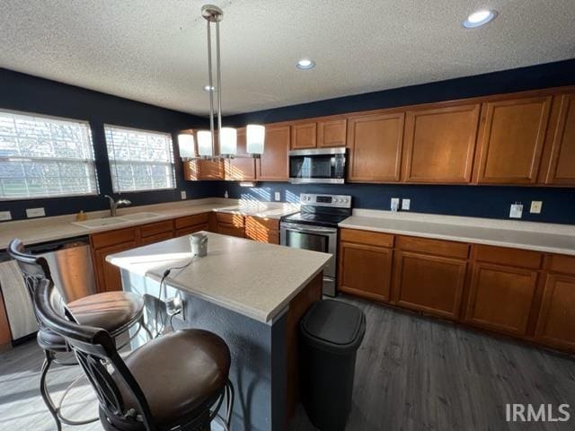 kitchen with dark hardwood / wood-style floors, decorative light fixtures, sink, stainless steel appliances, and a textured ceiling