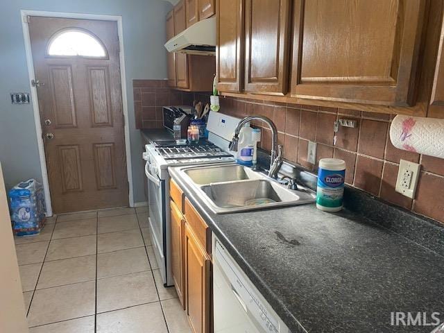 kitchen with sink, white appliances, light tile patterned floors, and backsplash