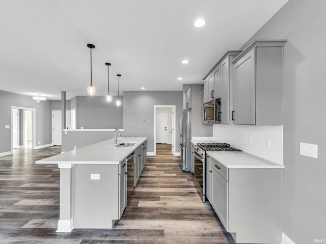 kitchen featuring sink, gray cabinets, appliances with stainless steel finishes, a kitchen island with sink, and hanging light fixtures