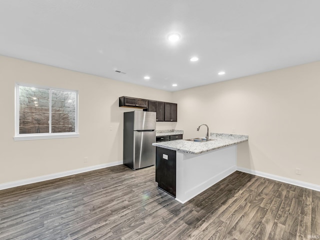 kitchen with light stone countertops, dark hardwood / wood-style floors, sink, and stainless steel fridge