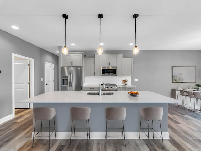 kitchen featuring pendant lighting, appliances with stainless steel finishes, gray cabinets, and sink