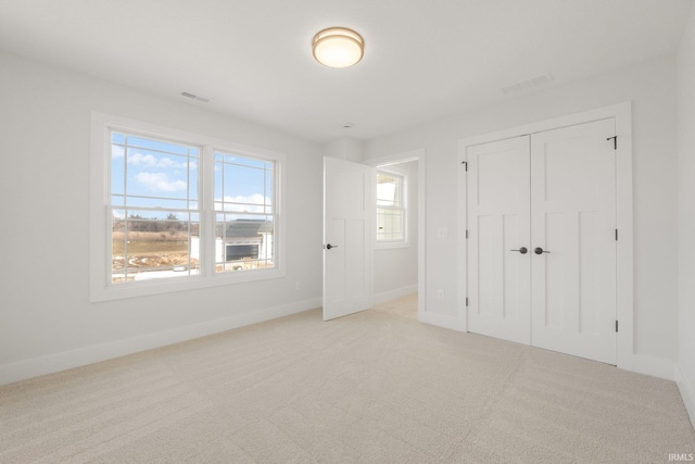 unfurnished bedroom with a closet and light carpet