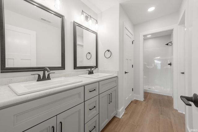 bathroom with wood-type flooring, vanity, and a shower