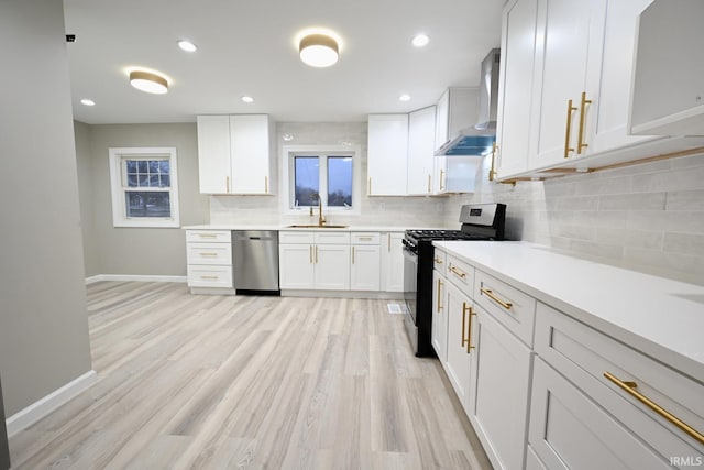 kitchen featuring white cabinetry, backsplash, light hardwood / wood-style floors, stainless steel appliances, and wall chimney range hood