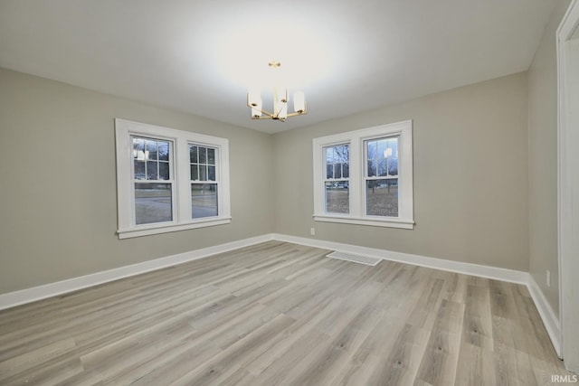 unfurnished room featuring an inviting chandelier and light hardwood / wood-style flooring