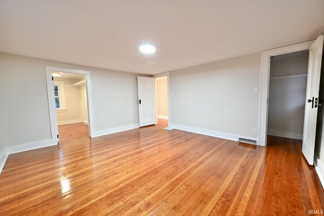 unfurnished bedroom featuring a spacious closet, light hardwood / wood-style floors, and a closet