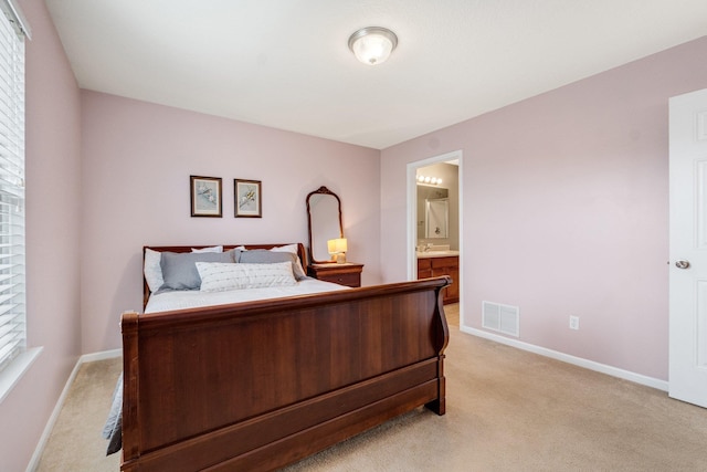 bedroom featuring ensuite bathroom and light carpet