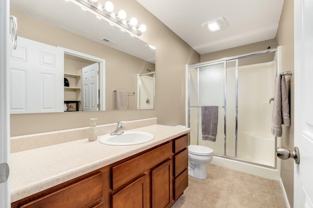 bathroom with vanity, toilet, a shower with shower door, and tile patterned flooring