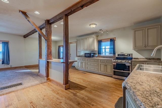 kitchen featuring double oven range, beam ceiling, light hardwood / wood-style flooring, and sink