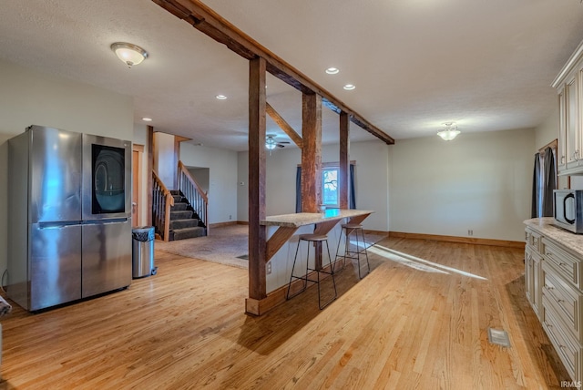 kitchen with stainless steel appliances, a breakfast bar, and light hardwood / wood-style flooring