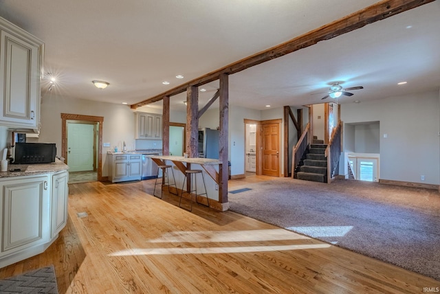 kitchen featuring ceiling fan, a breakfast bar area, light hardwood / wood-style floors, and dishwasher