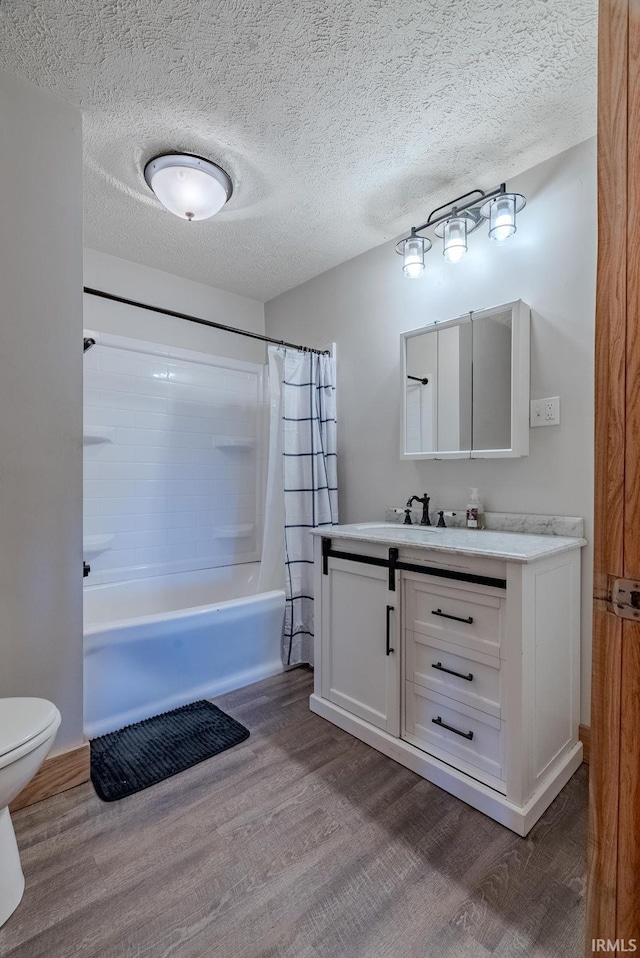 full bathroom featuring shower / bathtub combination with curtain, hardwood / wood-style floors, vanity, and a textured ceiling