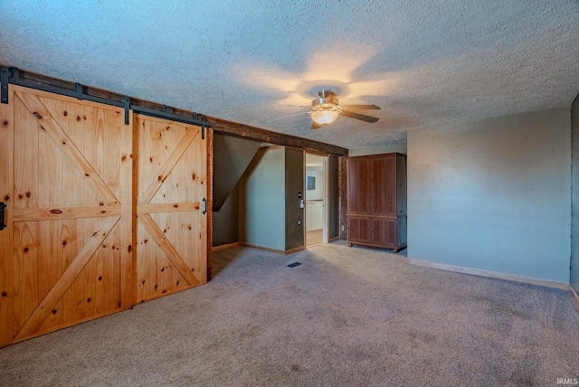 interior space featuring ceiling fan, a barn door, and a textured ceiling