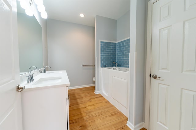 bathroom with vanity, a tub to relax in, wood-type flooring, and toilet