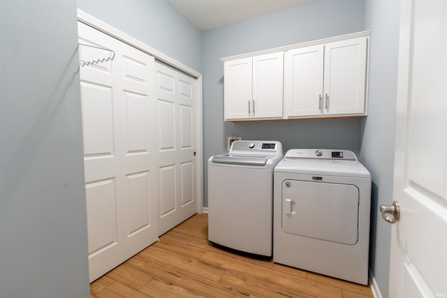 laundry area featuring cabinets, washing machine and clothes dryer, and light wood-type flooring