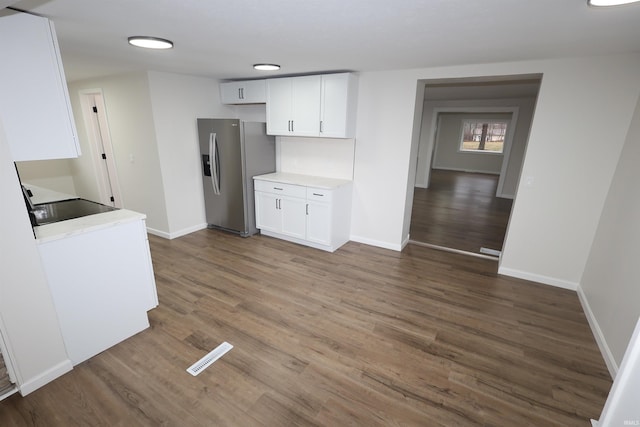 kitchen with white cabinetry, dark hardwood / wood-style floors, black electric stovetop, and stainless steel fridge