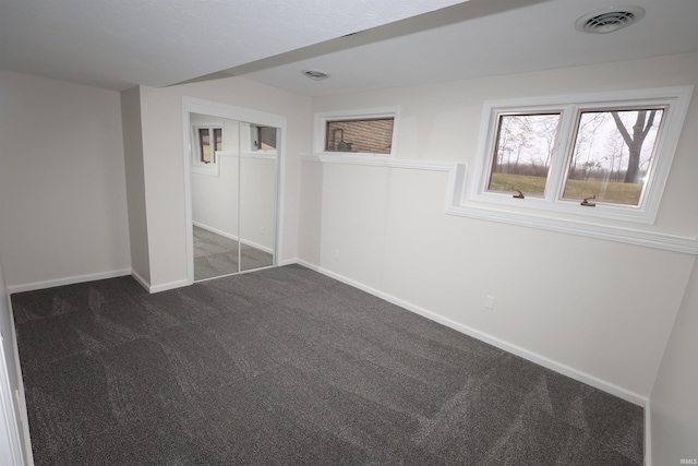 unfurnished bedroom with a closet and dark colored carpet