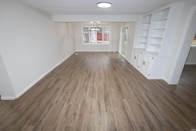 interior space with dark hardwood / wood-style flooring, built in features, and a notable chandelier