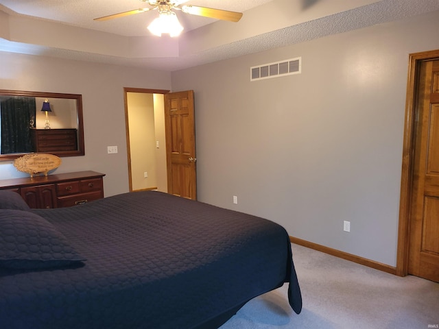 bedroom with light carpet, a tray ceiling, and ceiling fan