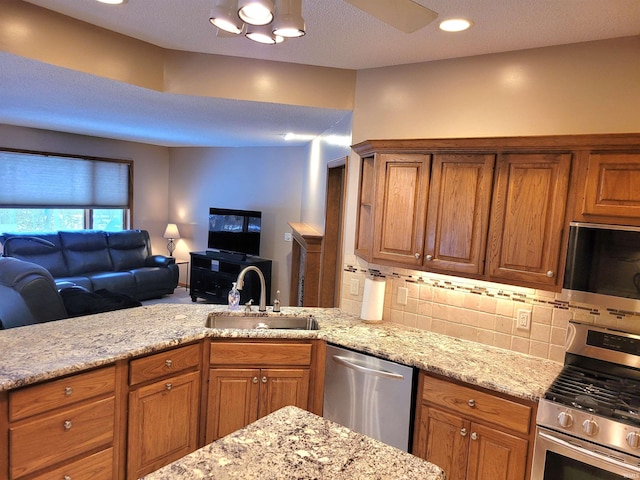 kitchen with tasteful backsplash, sink, light stone counters, and appliances with stainless steel finishes