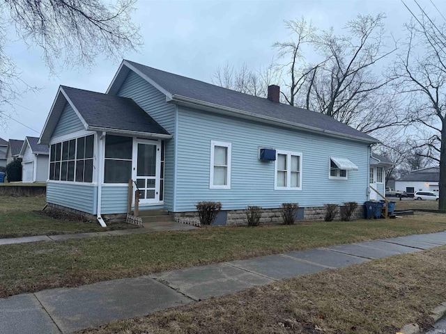 view of property exterior with a sunroom and a lawn