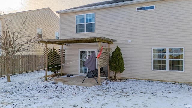 snow covered rear of property with a pergola