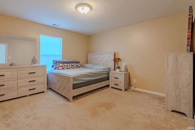 bedroom with light colored carpet and a textured ceiling