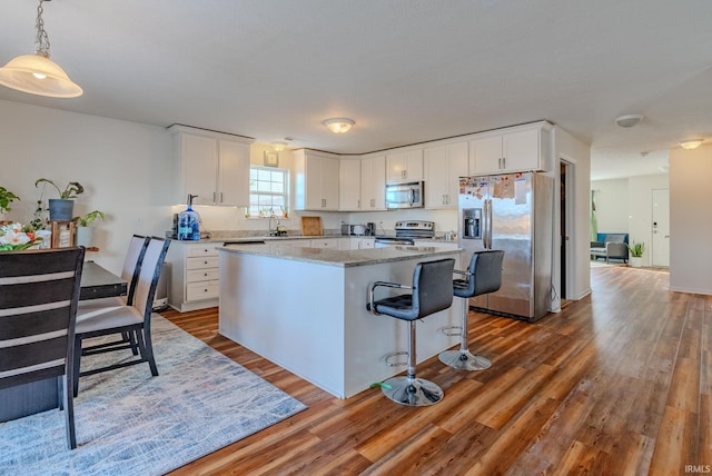 kitchen featuring pendant lighting, a center island, white cabinets, and appliances with stainless steel finishes