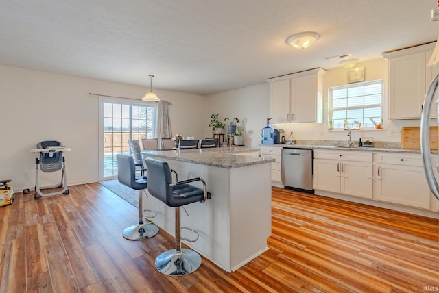 kitchen with white cabinetry, light stone counters, decorative light fixtures, a center island, and dishwasher