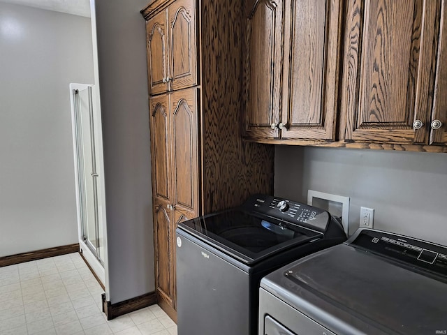 clothes washing area featuring cabinets and washing machine and clothes dryer