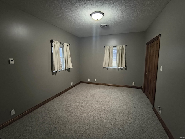 spare room featuring carpet and a textured ceiling