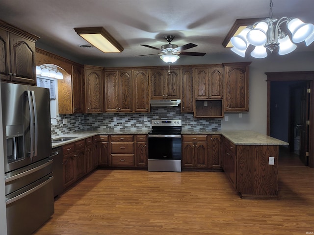 kitchen with stainless steel appliances, sink, hanging light fixtures, and light wood-type flooring