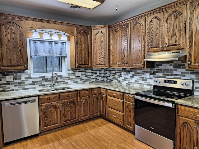 kitchen featuring stainless steel appliances, light stone countertops, sink, and light wood-type flooring