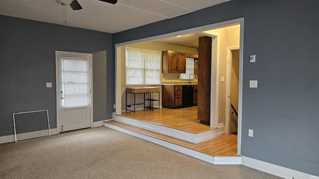 interior space with ceiling fan, light colored carpet, dishwasher, and sink